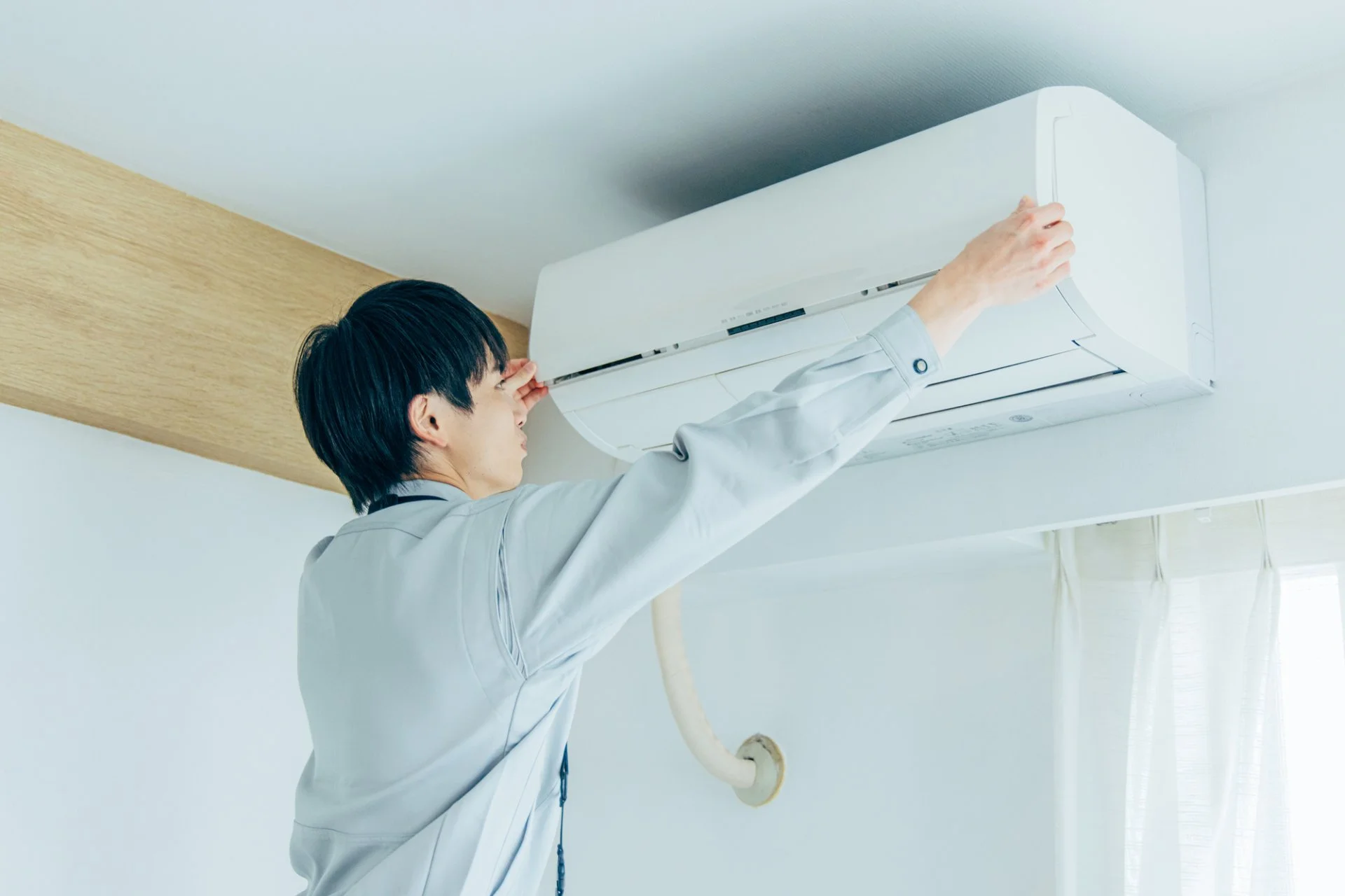 壁掛けエアコンの動作を確認する女性と点検を行う作業員